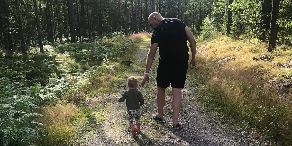 Vuxen och barn på stig i skog